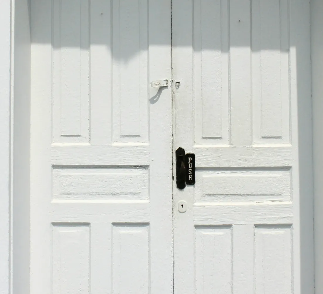 A plain white door, closed, as a fire door is meant to be kept