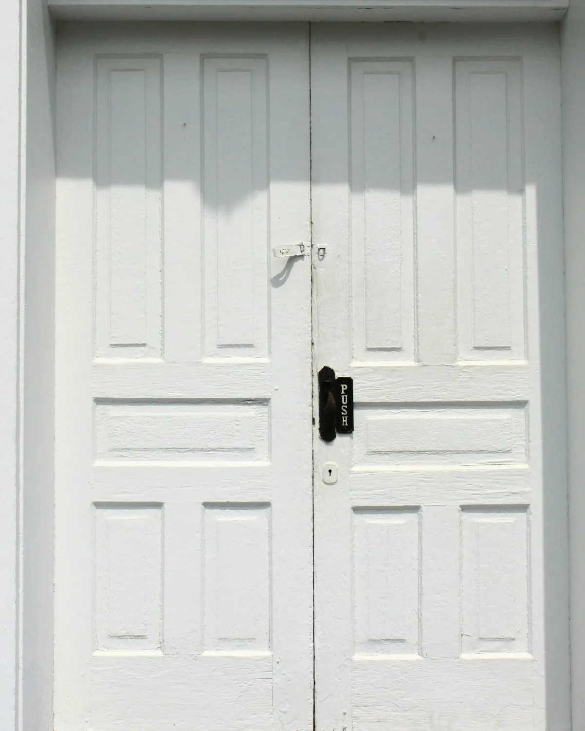 A plain white door, closed, as a fire door is meant to be kept