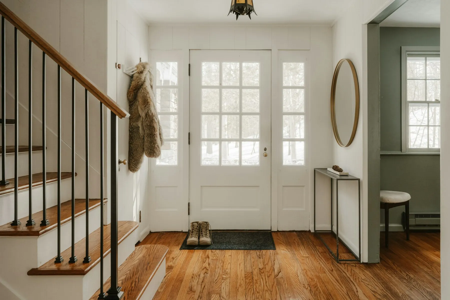 An entryway with a glazed door, timber stairs and morning light across the floor